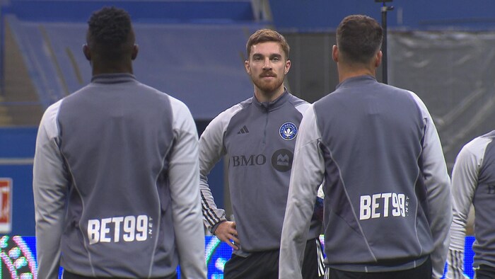 Joel Waterman, dans un survêtement gris du CF Montréal, regarde ses coéquipiers pendant la séance d'entraînement du club montréalais.