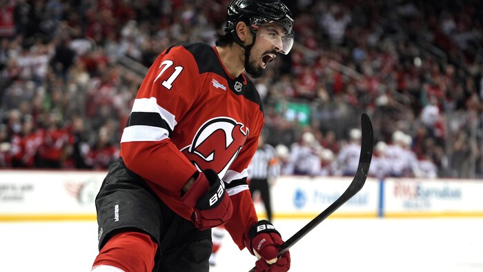 Un joueur de hockey en rouge exulte après avoir marqué. 
