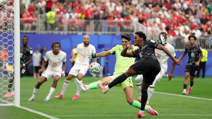 Un joueur de soccer effectue un tir, contré par le gardien adverse.