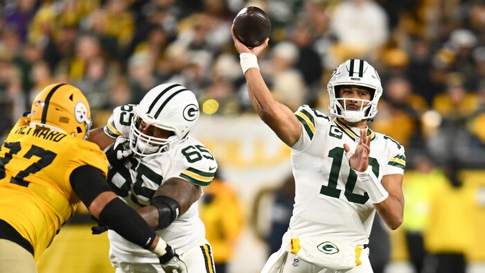 Un quart-arrière lance le ballon à côté de deux joueurs.