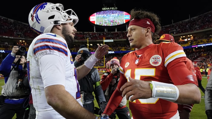 Les quarts-arrières Josh Allen et Patrick Mahomes s'enlacent sur un terrain de football.