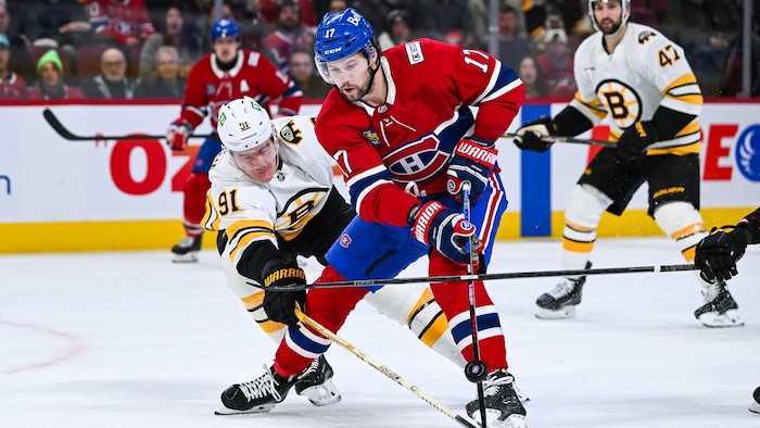 Un joueur de hockey avec la rondelle, devant un adversaire. 