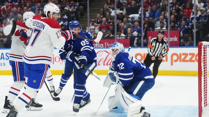 Un joueur de hockey frappe la rondelle dans les airs face à un gardien.