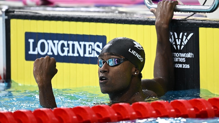 Un homme avec le poing levé dans une piscine.