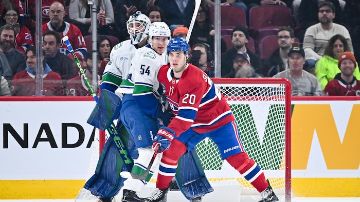 Un joueur du Canadien posté devant le filet, le gardien et un défenseur adverses.