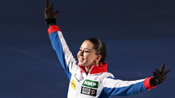 Une jeune patineuse porte un manteau aux couleurs de la Russie et sourit à la foule.