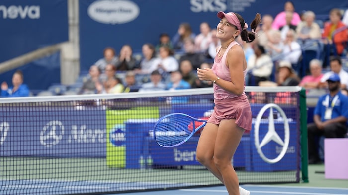 Une joueuse de tennis sourit après avoir gagné un point.