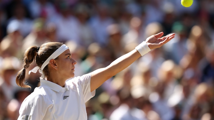 Une joueuse de tennis lance la balle pour servir.