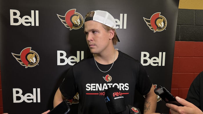 Un joueur de hockey répond aux questions des journalistes dans une mêlée de presse.