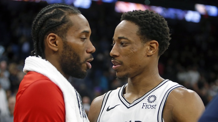 Kawhi Leonard (en rouge) et DeMar DeRozan (en blanc) se font une accolade à la suite d'un match entre les Raptors de Toronto et les Spurs de San Antonio.