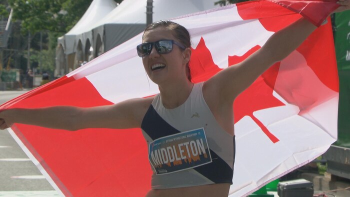 Kinsey Middleton sourit avec le drapeau du Canada dans ses mains.