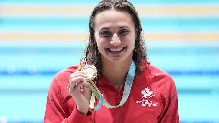 Une femme pose avec sa médaille d'or. 