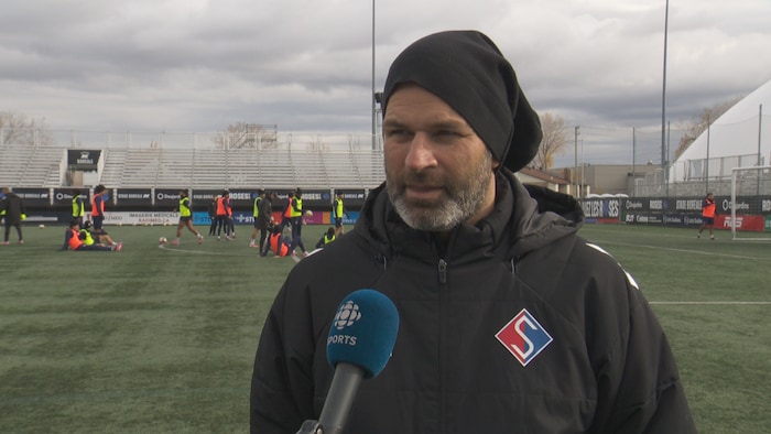 Un entraîneur de soccer parle à un micro.