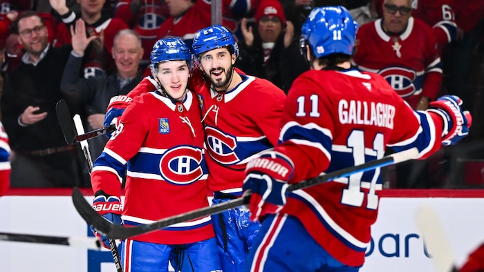 Trois joueurs de hockey s'enlacent.