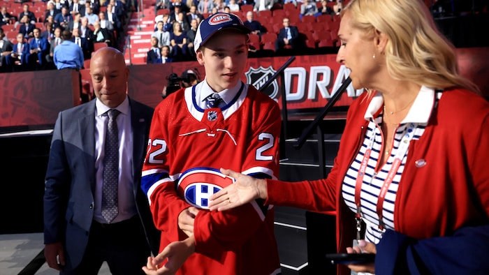 Un joueur de hockey fraîchement repêché entouré d'un homme et d'une femme