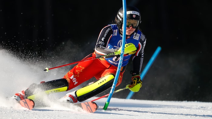 La skieuse repousse un piquet du bras gauche.