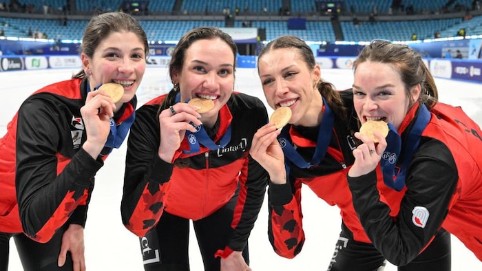 Quatre femmes posent en mordant une médaille d'or.      