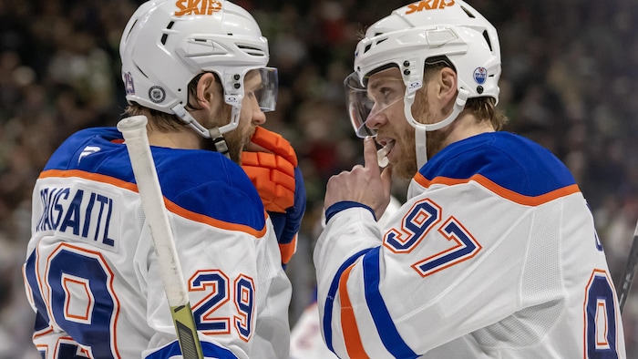 Deux hockeyeurs discutent durant un arrêt de jeu.