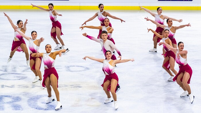 Onze patineuses et un patineur sont sur la glace.