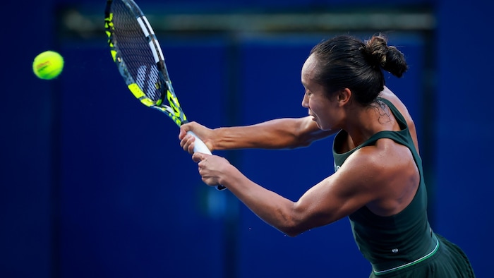 Une joueuse de tennis frappe un revers.