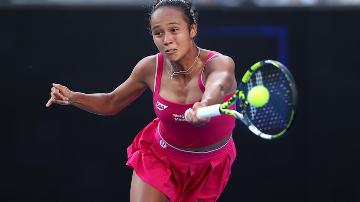 Une joueuse de tennis en roseate retourne une balle.