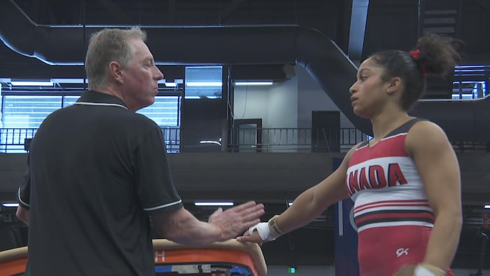 Une gymnaste discute avec un homme près d'une table de saut.