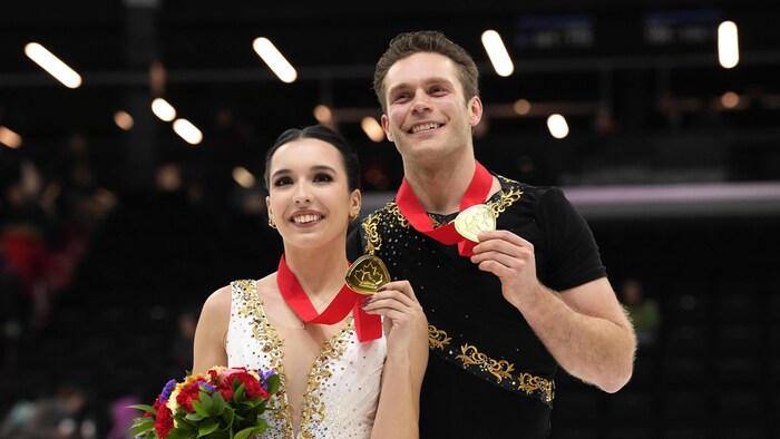 Deux patineurs posent avec leur médaille d'or au cou.
