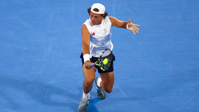 Un joueur de tennis frappe un revers.