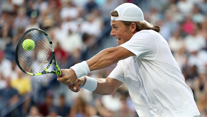 Un joueur de tennis frappe un revers.