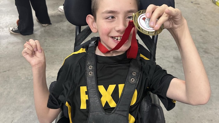Jeune garçon montrant médaille.
