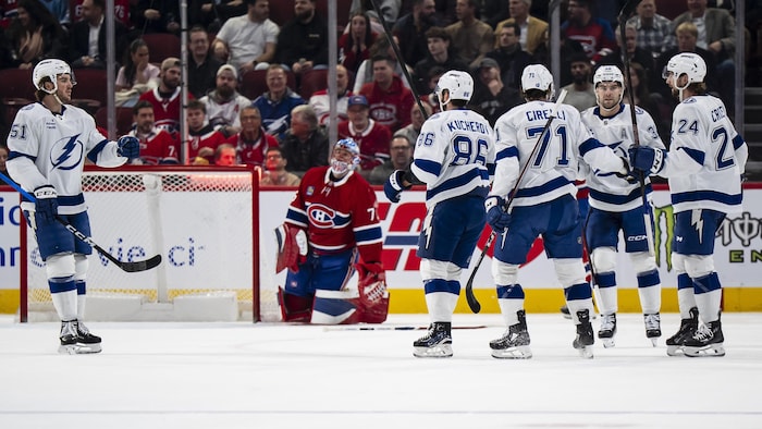 Des joueurs d'une équipe célèbrent un but devant le gardien adverse. 