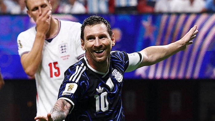 Un joueur de soccer sourit, devant un adversaire à la mine basse.