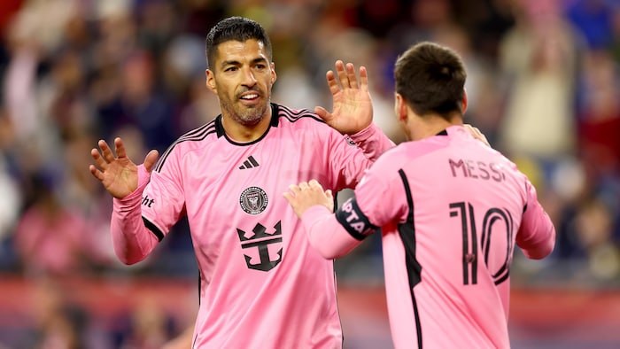 Deux joueurs de soccer se félicitent après avoir marqué un but. Ils portent des uniformes roses.