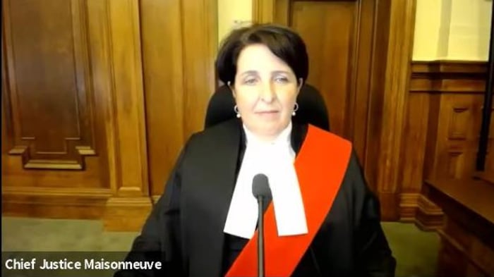 Une femme en tenue de juge est assise derrière un micro.