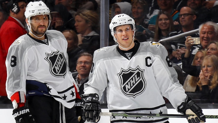 Deux joueurs de hockey sont sur la glace lors d'un match des étoiles.