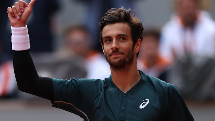 Un joueur de tennis salue la foule. 