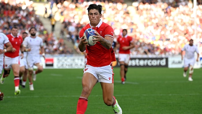 Un joueur de rugby tient un ballon à deux mains.