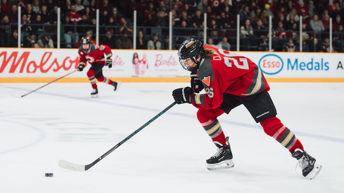 Une joueuse de hockey transporte la rondelle et se dirige en zone adverse pendant une rencontre.