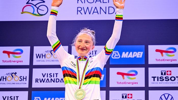 Médaille d'or au cou, elle lève les mains sur le podium.