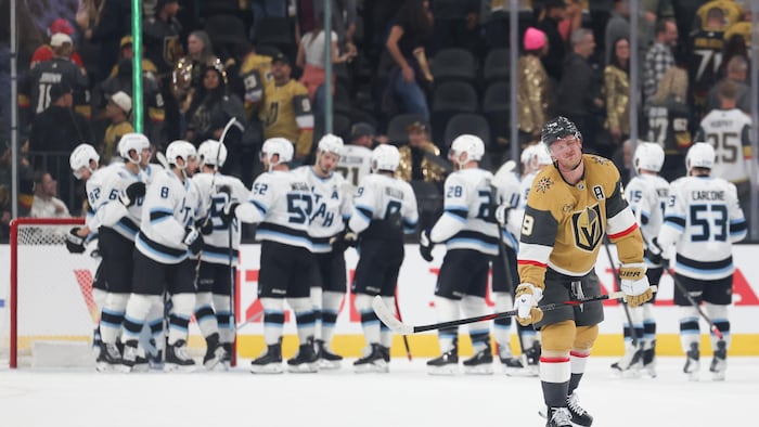 Des joueurs en blanc se félicitent sur la glace après leur victoire.