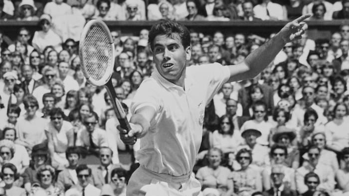 Dans une photo d'archives des années 60, un joueur de tennis frappe la balle du revers avec une raquette de bois.