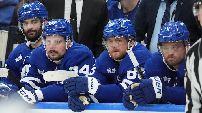 Des joueurs de hockey en bleu à leur banc.