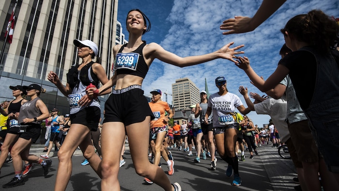 Une femme court en souriant lors du marathon d'Ottawa.