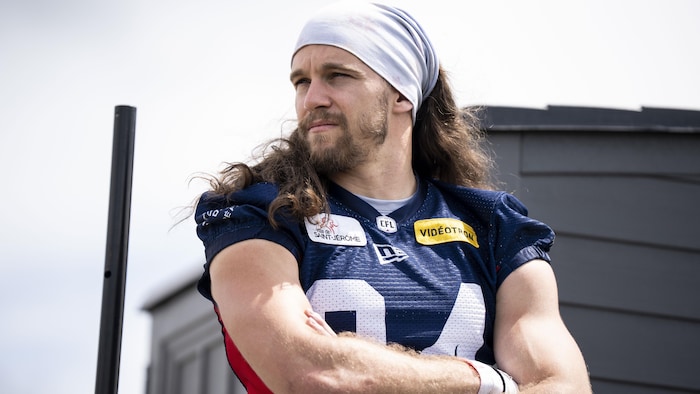 Un footballeur, sans son casque, regarde au loin.