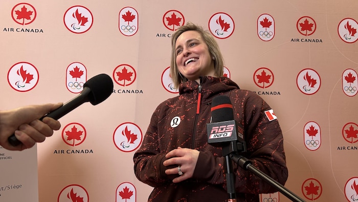 Une athlète sourit devant deux micros. 