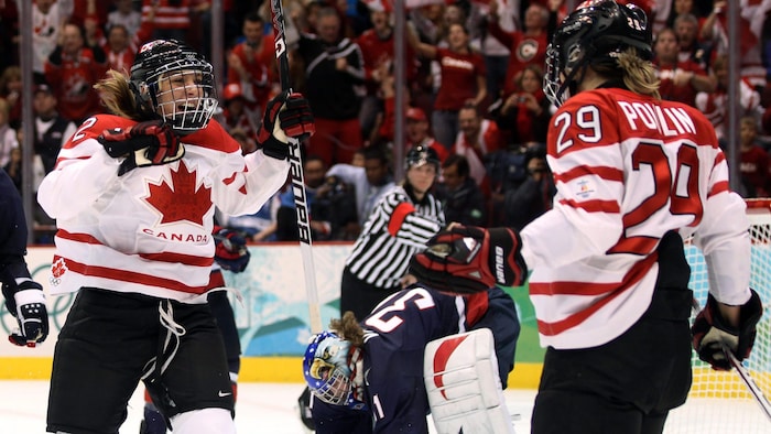 Deux joueuses en blanc célèbrent un but. 