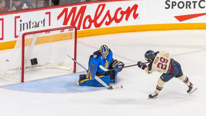 Une hockeyeuse marque un but contre une gardienne.