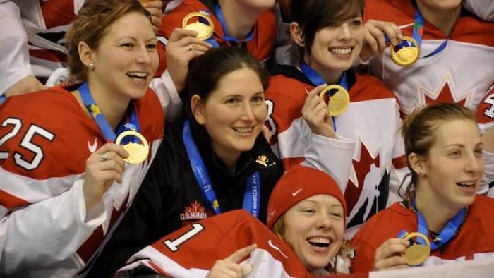 Joueuses de hockey, souriantes, montrant leurs médailles.