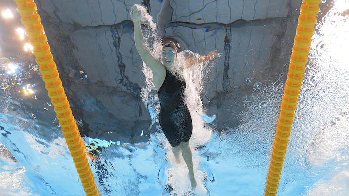 Une femme nage dans une piscine.