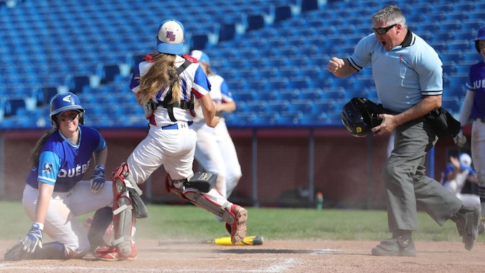 Un arbitre de baseball retire une joueuse au marbre pendant un match.
